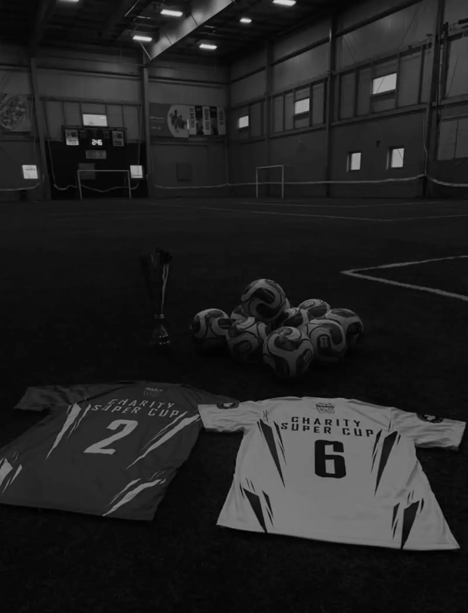 Charity Super Cup jerseys, trophy, and match balls laid out on the pitch