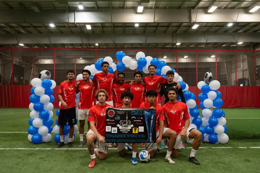 Team celebrating with the Charity Super Cup trophy and sponsor banner