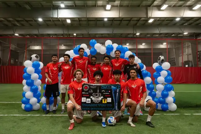 Team celebrating with the Charity Super Cup trophy and sponsor banner