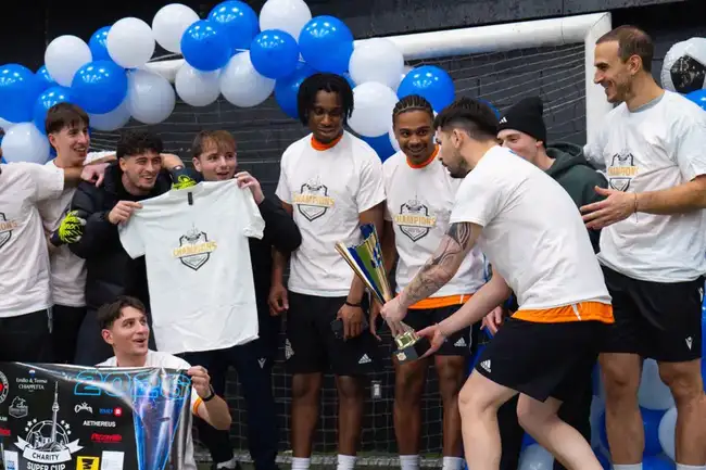 Champions celebrating with the trophy in their Charity Super Cup shirts