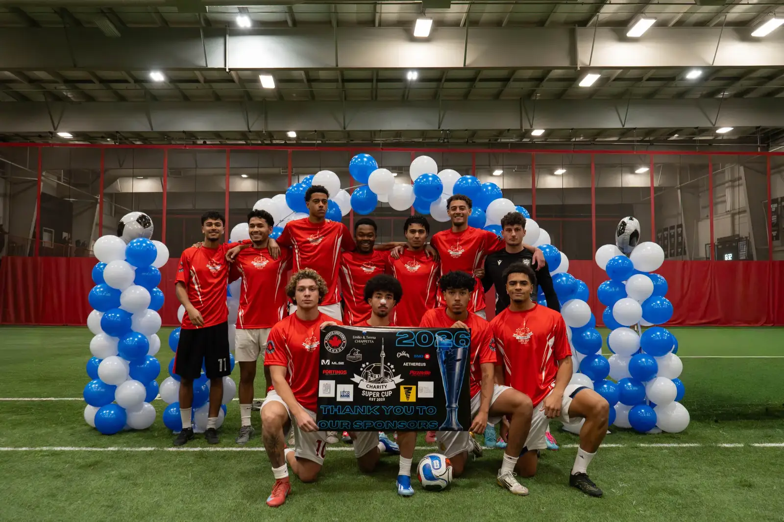 Charity Super Cup team photo with sponsor thank-you banner and trophy